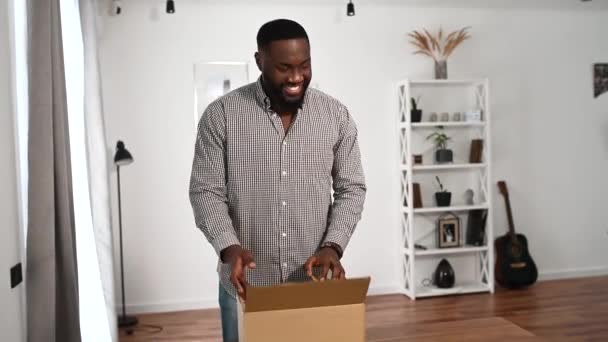 En afrikansk kille packar upp en paketlåda — Stockvideo