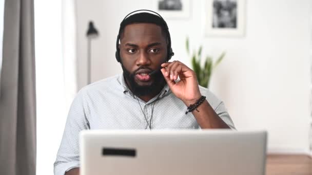 Een Afro-Amerikaan gebruikt headset en laptop voor zijn werk. — Stockvideo