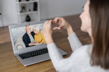 Dizüstü bilgisayarda büyükanne ve büyükbabasıyla video görüşmesi, ekranda yaşlı bir çift.