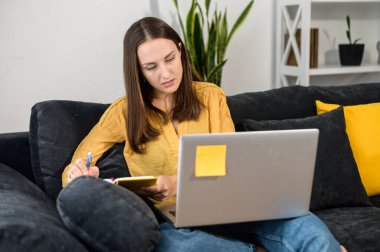 Evde dizüstü bilgisayarı olan genç bir kadın.