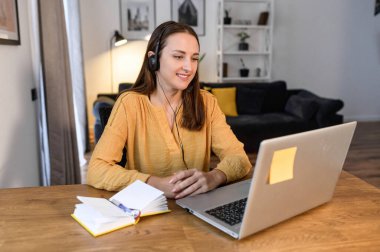 Evde dizüstü bilgisayarı olan genç bir kadın.