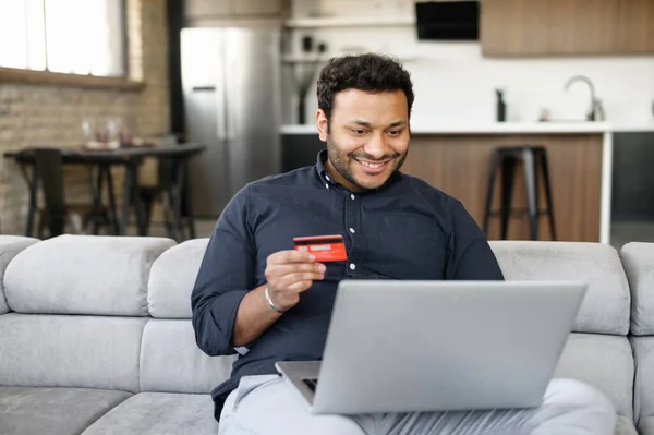 Gelukkige indiaanse man met een creditcard en online betalen — Stockfoto