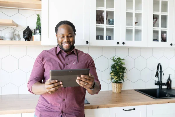 Neşeli ve pozitif Afro-Amerikalı adam dijital tabletin dokunmatik ekranında kayıyor.