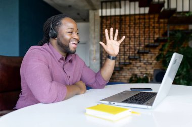 Saçları bukleli, kablosuz kulaklık takan mutlu Afro-Amerikalı adam.