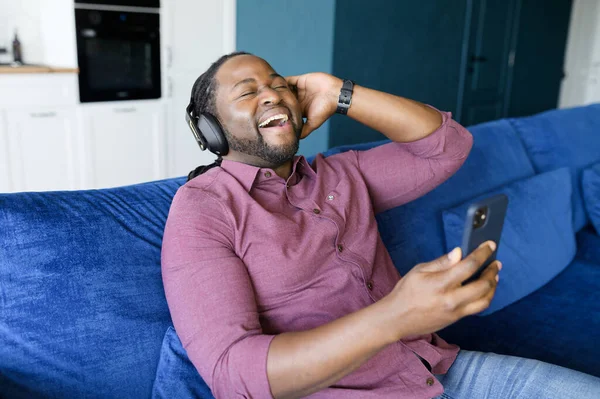 Emocionado hombre afroamericano con auriculares escuchando música — Foto de Stock