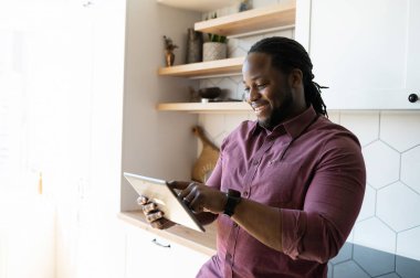 Neşeli ve pozitif Afro-Amerikalı adam dijital tabletin dokunmatik ekranında kayıyor.
