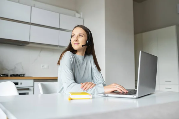 Mujer joven positiva con auriculares habla en línea — Foto de Stock