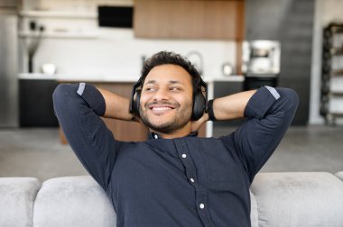 Huzurlu ve mutlu melez adam kulaklık takıp müzik dinliyor.