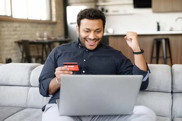 Cara indiana feliz segurando cartão de crédito e pagando online — Fotografia de Stock