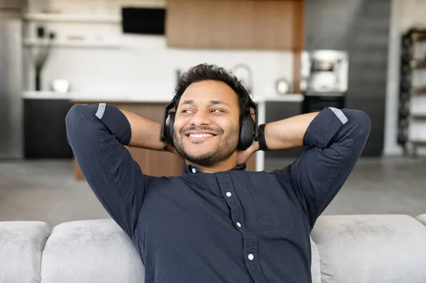 Sereno y feliz tipo de raza mixta con auriculares escuchando música —  Fotos de Stock