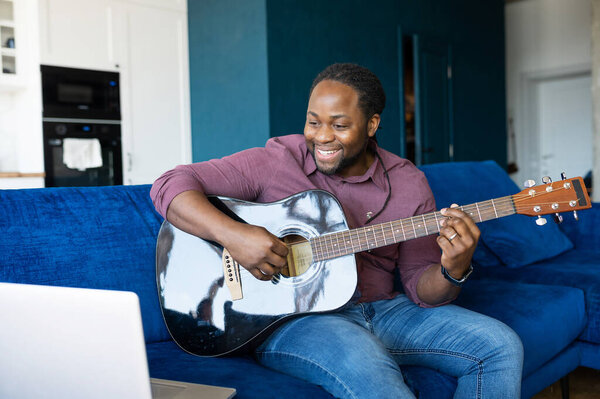 African-American guy playing acoustic guitar and streaming online