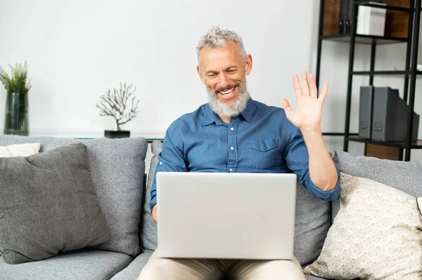 Uomo anziano allegro contemporaneo che usa il computer portatile per connessione video — Foto Stock