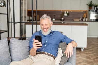 Çağdaş karizmatik, gündelik gömlekli, akıllı telefon kullanan olgun bir adam.