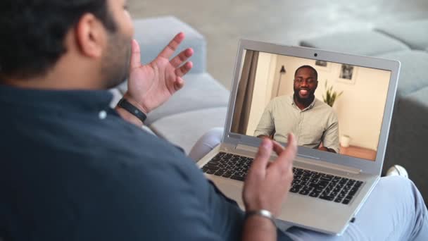アフリカ系アメリカ人男性の同僚とビデオ接続のためのコンピュータアプリを使用してインドの男 — ストック動画
