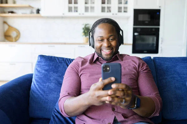 Chico afroamericano usando teléfono inteligente sentado en casa — Foto de Stock