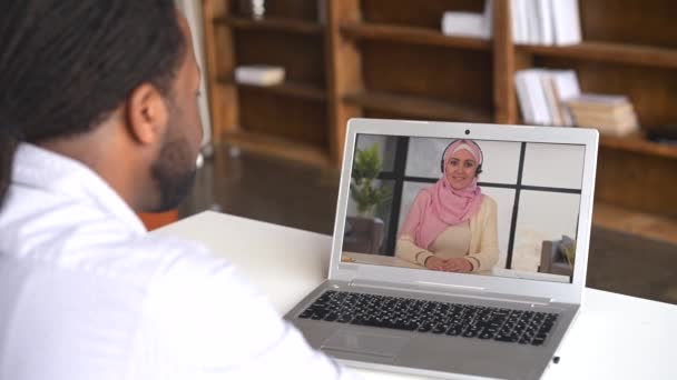 Ein afroamerikanischer männlicher Büroangestellter mit einem Laptop für ein Videotreffen — Stockvideo