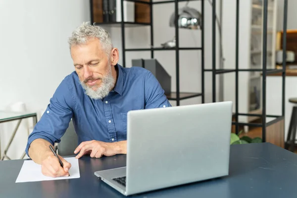 Absorbido pensativo hombre de negocios senior en camisa casual inteligente se sienta en el escritorio —  Fotos de Stock