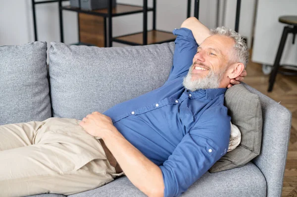 Mężczyzna w średnim wieku leży na kanapie i odpoczywa — Zdjęcie stockowe