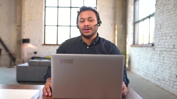 Συμπυκνωμένος Ινδός άνδρας που φοράει ασύρματα ακουστικά χρησιμοποιώντας φορητό υπολογιστή για απομακρυσμένη σύνδεση — Αρχείο Βίντεο