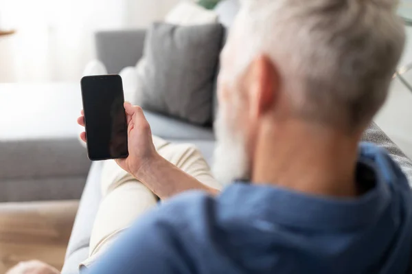 Керуючий середнього віку тримає смартфон з чорним порожнім екраном — стокове фото