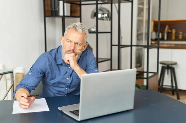 Absorbido pensativo hombre de negocios senior en camisa casual inteligente se sienta en el escritorio —  Fotos de Stock