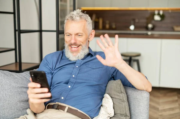 Samtida karismatisk mogen man i avslappnad skjorta med smartphone för videosamtal — Stockfoto