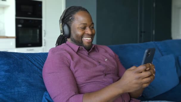 Hombre afroamericano en auriculares pasa tiempo libre viendo películas — Vídeo de stock