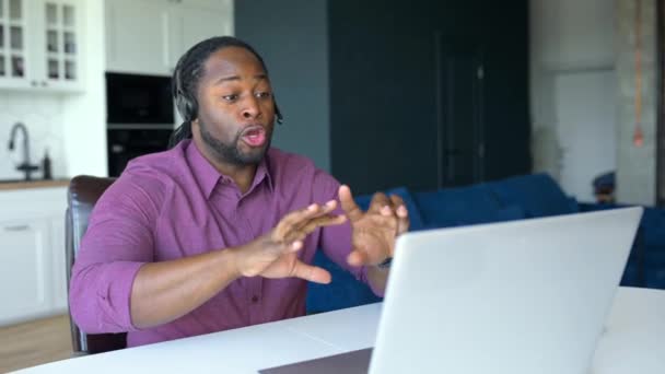 Feliz hombre afroamericano con mechones de pelo con auriculares inalámbricos sentados en casa — Vídeos de Stock