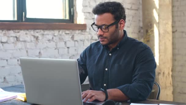 Individuo freelancer hindú enfocado usando anteojos usando laptop — Vídeo de stock