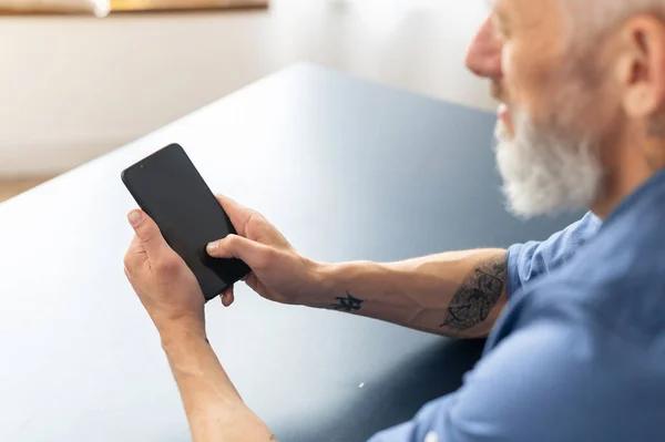 Back view over shoulder of senior man at the smartphone with blank screen