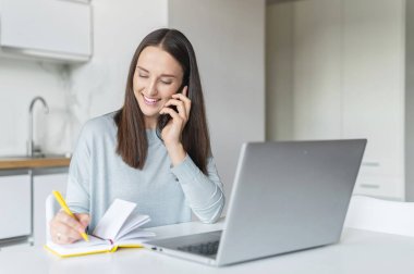 Evde çalışmak için dizüstü bilgisayar kullanan çekici genç bir kadın.