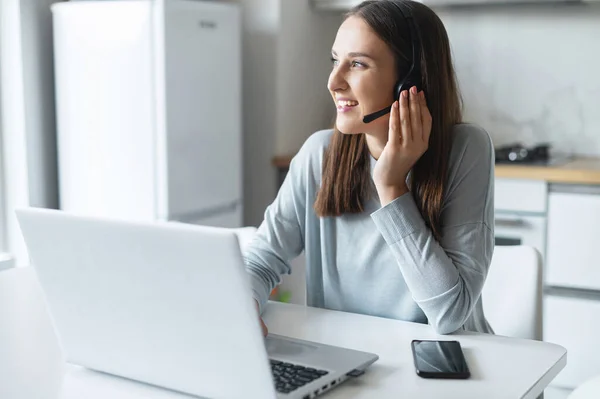 Mujer joven positiva con auriculares habla en línea —  Fotos de Stock