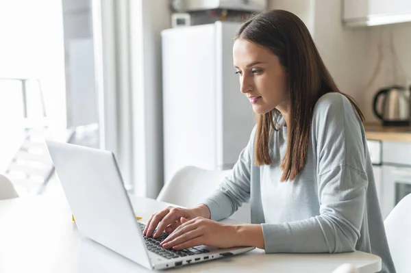 Jovem encantadora usando computador portátil para trabalhar em casa — Fotografia de Stock