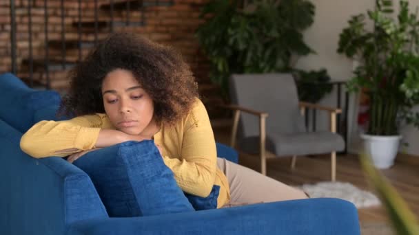 Femme afro-américaine bouleversée se sent ennuyée assis sur le canapé à la maison seul — Video
