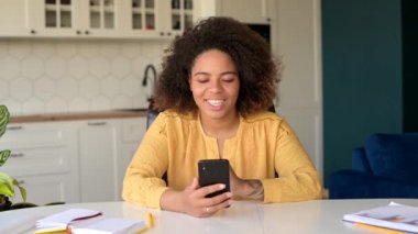 İyimser Afro-Amerikalı kadın akıllı telefondan video ile konuşuyor.