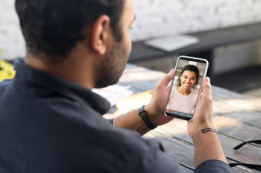 Video toplantısı için cep telefonu uygulaması kullanan çok ırklı bir adam