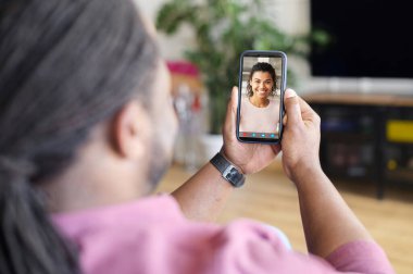 Bir adam internette genç bir kadınla sohbet etmek için akıllı telefon kullanıyor.