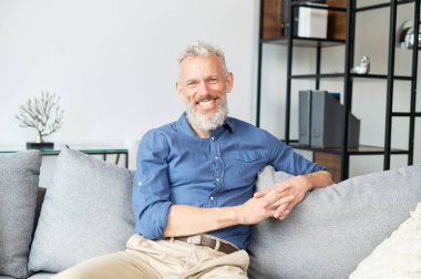 Yakışıklı, iyimser, olgun bir adam neşeli bir gülümsemeyle kameraya bakıyor.