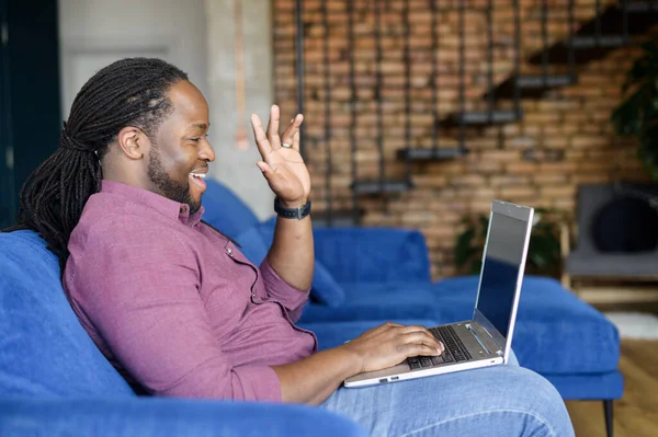 Smiling and happy African-American guy makes video call on the laptop
