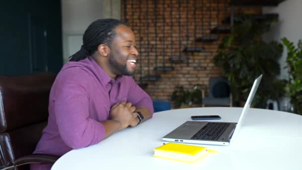 Hilarante afroamericano freelancer masculino con camisa casual usando portátil para videollamada — Vídeos de Stock
