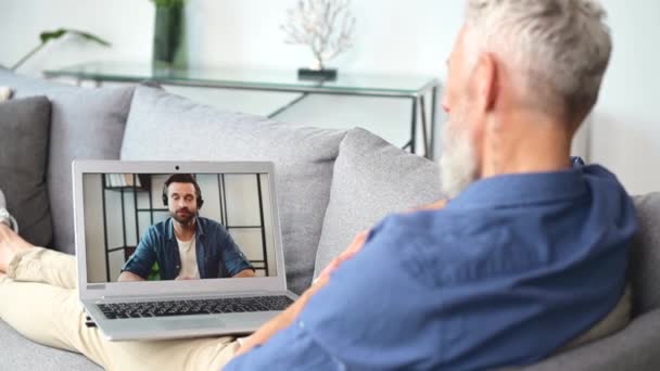 Старший человек использует компьютерное приложение для онлайн-общения с коллегами-мужчинами — стоковое видео