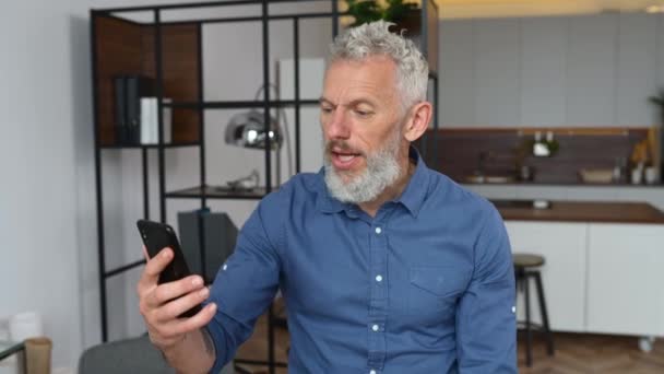 Седой бизнесмен в умной повседневной одежде использует смартфон для видеосвязи — стоковое видео