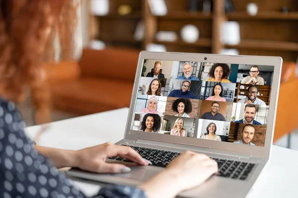 Mujer rizada sentada en la computadora portátil, charlando con sus colegas a través de una reunión de video —  Fotos de Stock