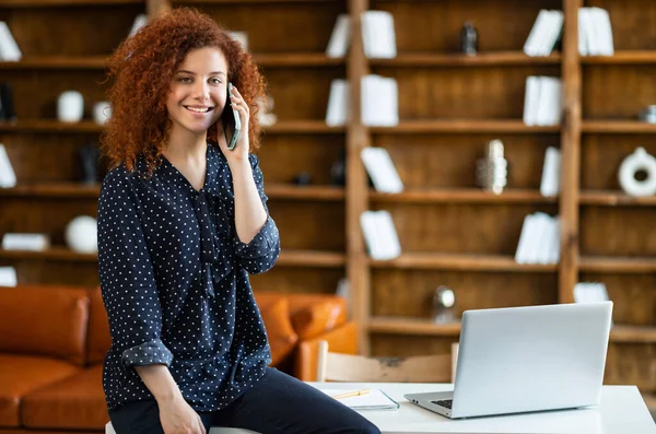 Trabajadora de oficina sonriente con el pelo rizado hablando por teléfono móvil —  Fotos de Stock