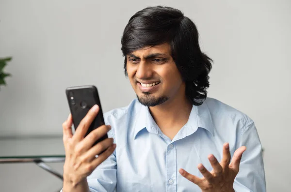 Annoyed indian businessman is holdng the smartphone