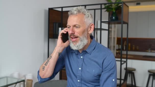 Hombre de negocios contemporáneo de mediana edad en ropa casual inteligente hablando en el teléfono inteligente — Vídeos de Stock