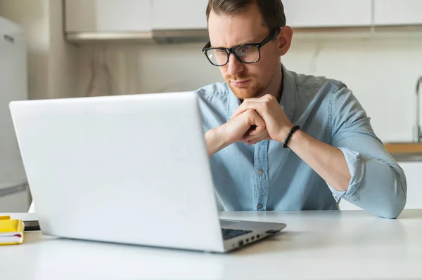 Jovem empresário focado usando laptop para trabalho remoto em casa — Fotografia de Stock