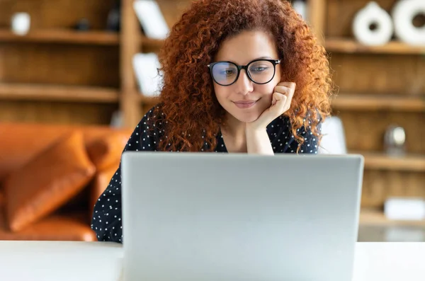 Freelancer feminino encaracolado ruivo bonito usando laptop — Fotografia de Stock