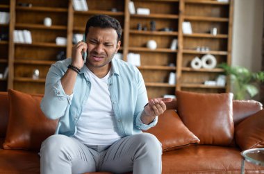 Sinirli Hintli adam hoş olmayan bir telefon görüşmesi yapıyor.