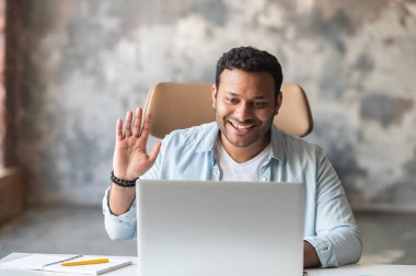 Hintli erkek çalışan video bağlantısı için dizüstü bilgisayar uygulaması kullanıyor.